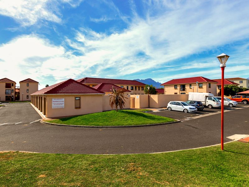 Exterior view of the apartment complex featuring paved driveways, landscaped grounds, and tiled roof structures.