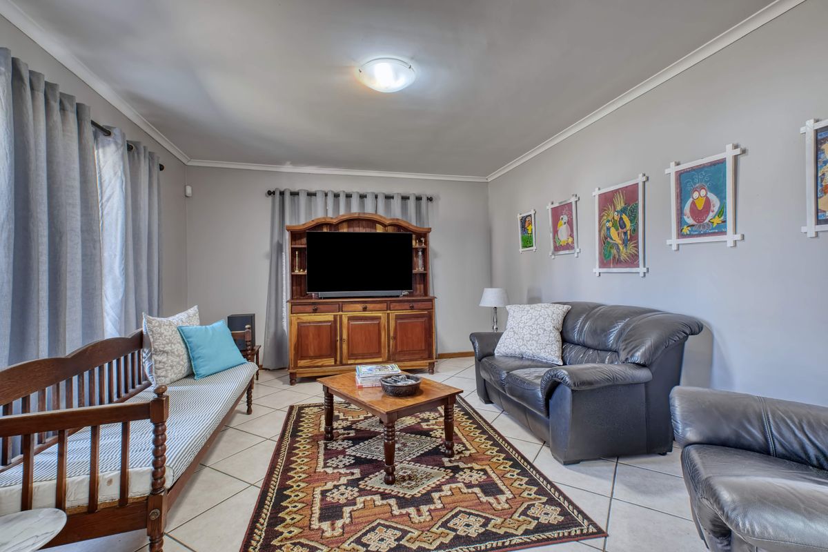 A comfortable living room featuring neutral wall tones, tiled flooring, and classic cove cornicing, providing a functional and well-maintained space.