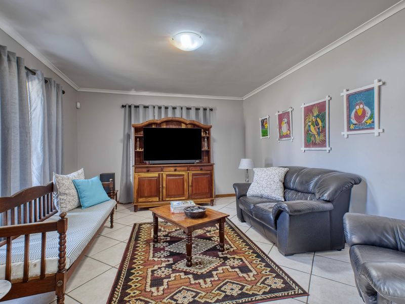 A comfortable living room featuring neutral wall tones, tiled flooring, and classic cove cornicing, providing a functional and well-maintained space.