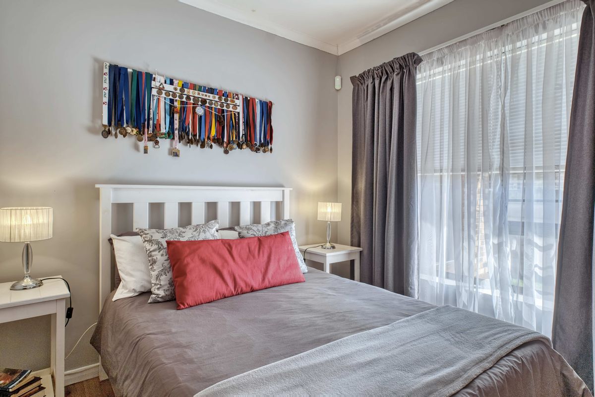 A well-maintained bedroom featuring neutral wall tones, coving, and a large window with layered curtains, providing a comfortable and bright living space.