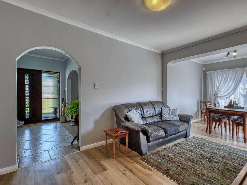 Open plan living and dining area featuring laminate flooring, an arched entryway, and a tiled foyer with a decorative front door.