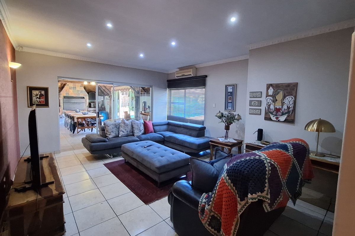 Spacious living room featuring tiled flooring, recessed downlighting, and large sliding glass doors providing seamless access to the outdoor patio area.