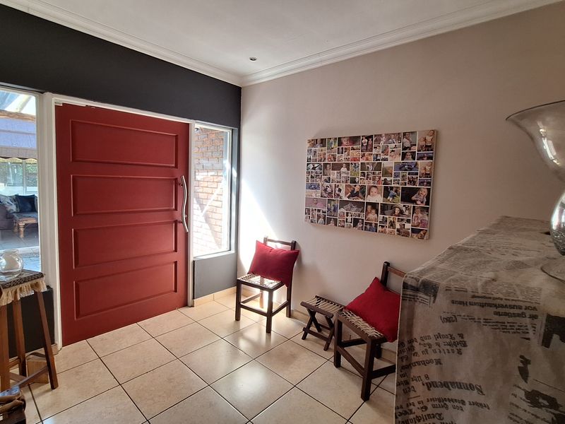 A bright entrance hall featuring tiled flooring, a bold red front door, and side light windows providing natural illumination.