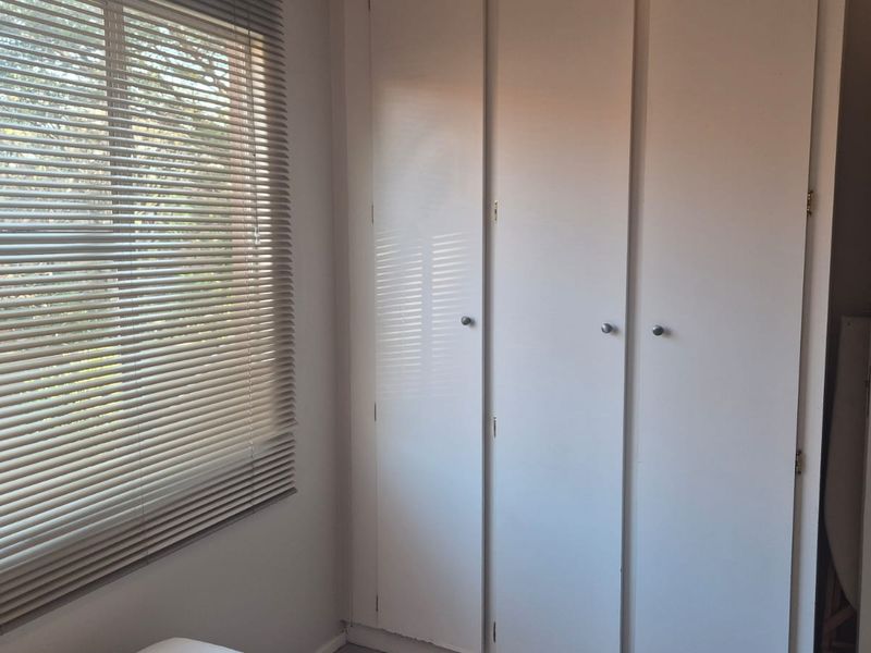 A bedroom featuring built-in cupboards and venetian blinds, offering a clean and functional space.