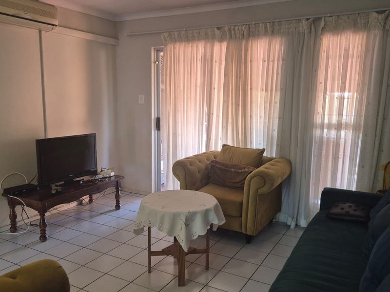 A living room featuring tiled flooring, an air conditioning unit, and a sliding glass door providing access to the exterior.