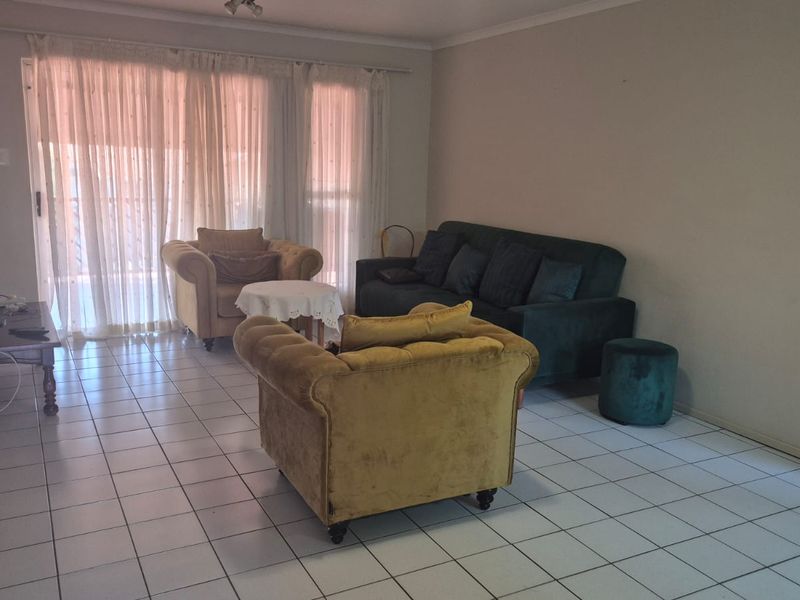 A spacious living room featuring tiled flooring, an air conditioning unit, and large sliding glass doors that provide access to the outdoor area.