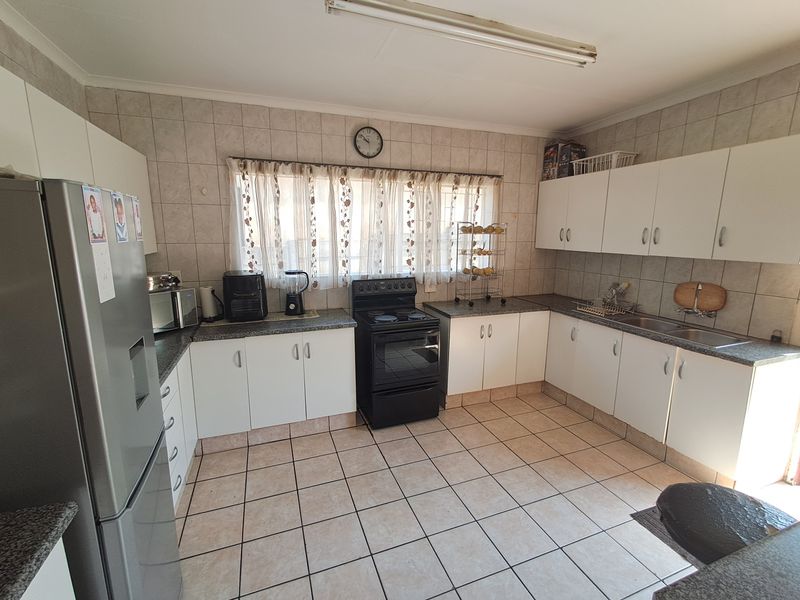 A functional kitchen featuring white cabinetry, granite countertops, tiled backsplash, and ceramic floor tiles, providing a practical layout for daily meal preparation.