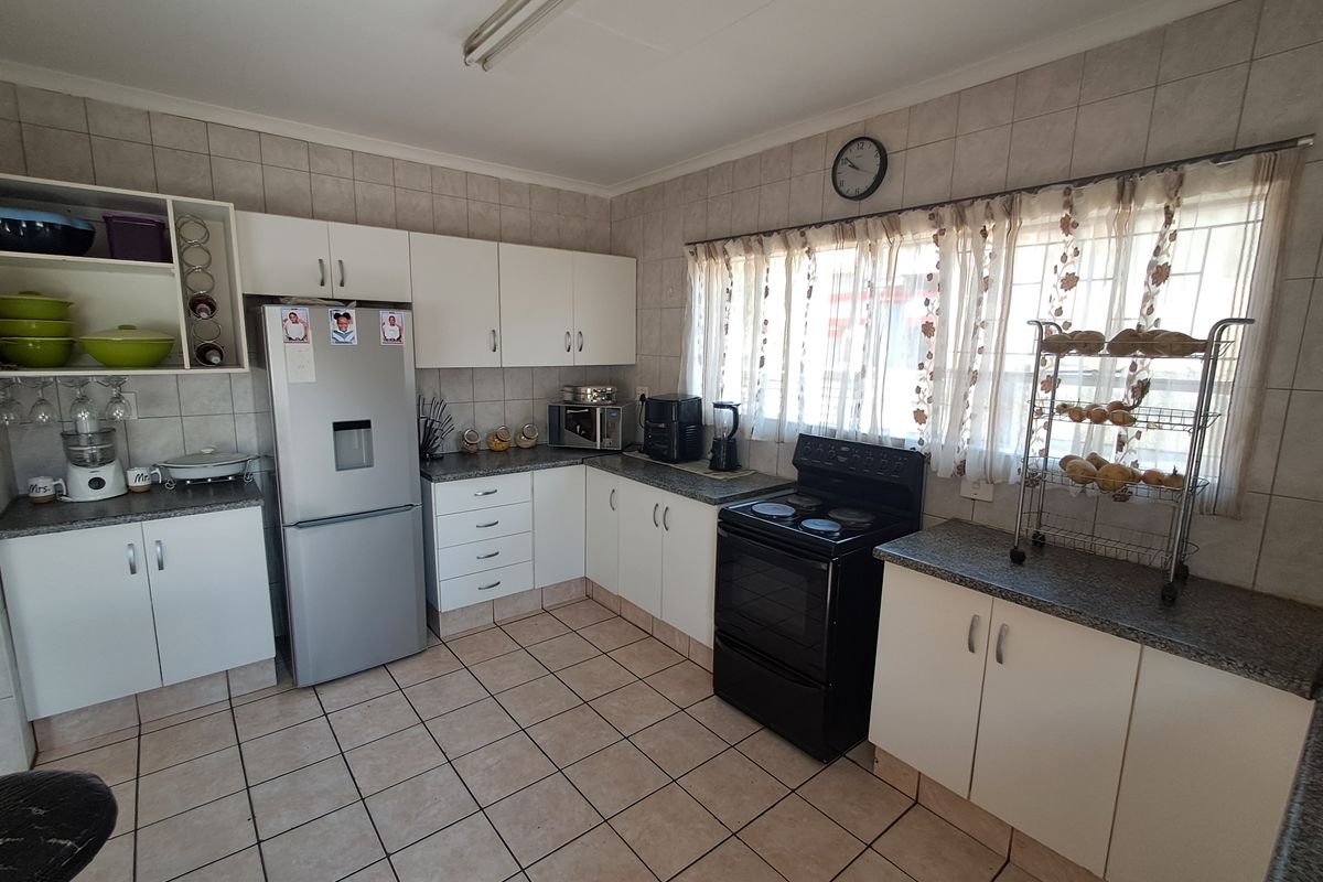 A functional kitchen featuring white cabinetry, laminate countertops, tiled flooring, and a tiled backsplash, providing a practical workspace with ample storage.