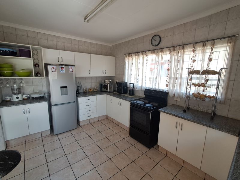 A functional kitchen featuring white cabinetry, laminate countertops, tiled flooring, and a tiled backsplash, providing a practical workspace with ample storage.