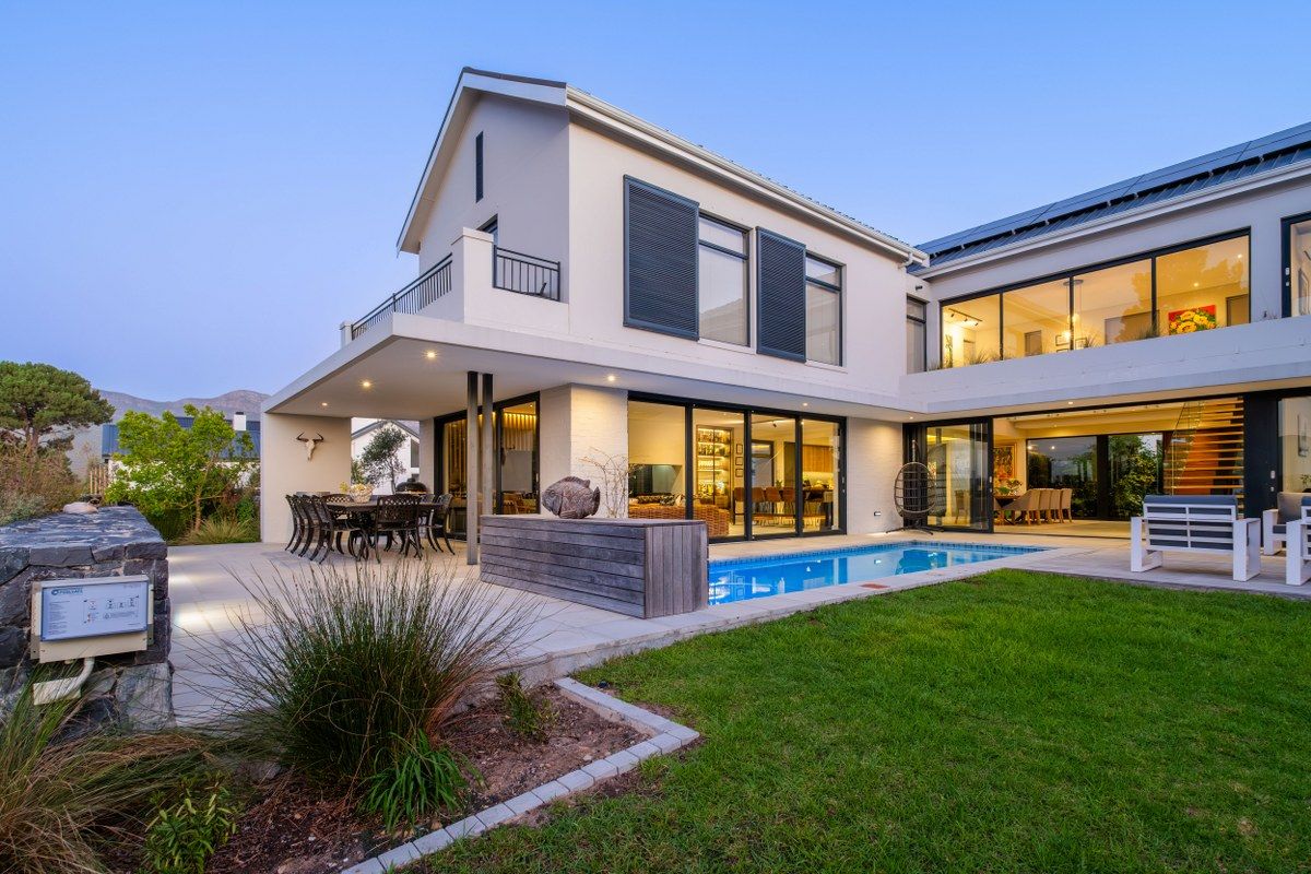 A modern double-story residence featuring a swimming pool, covered patio, and balcony, seamlessly blending indoor and outdoor living spaces.