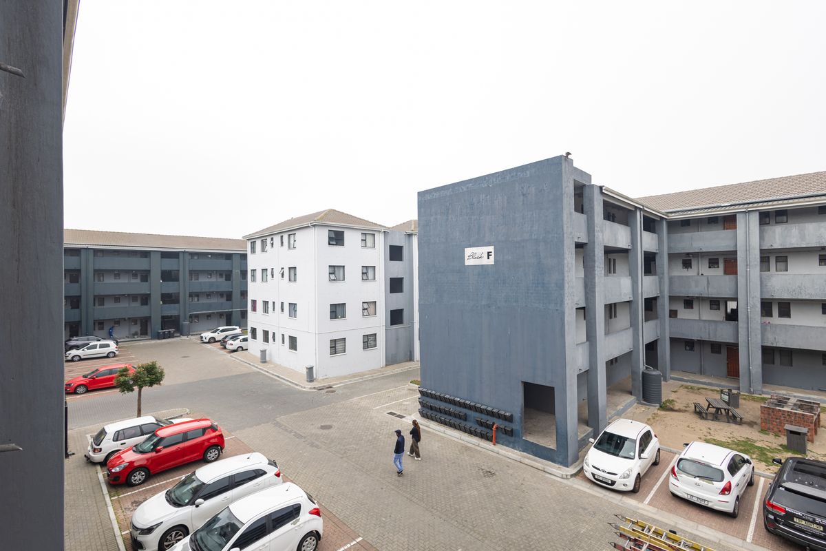 An elevated view of a residential apartment complex courtyard featuring paved parking, multiple building blocks, and communal outdoor facilities.