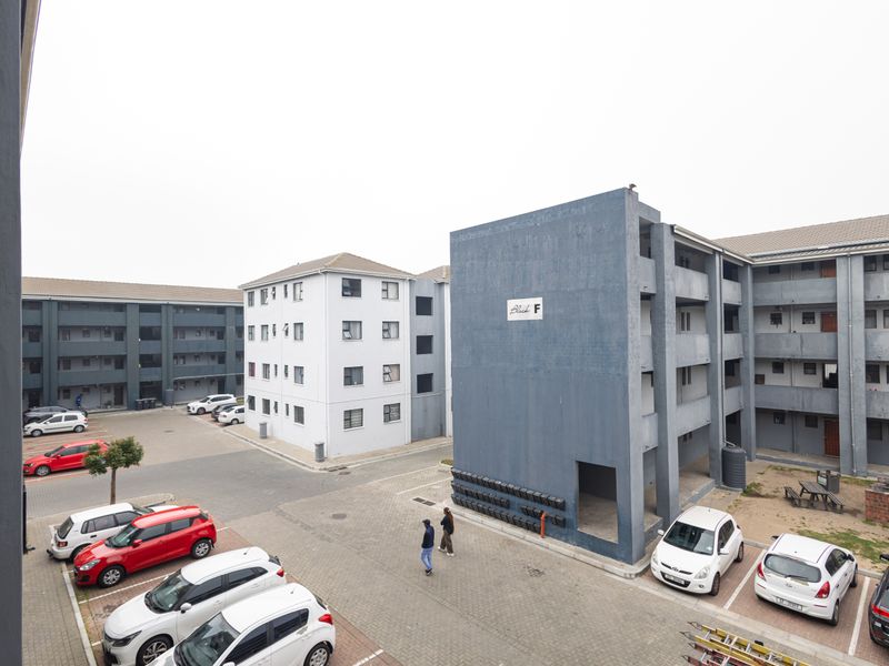 An elevated view of a residential apartment complex courtyard featuring paved parking, multiple building blocks, and communal outdoor facilities.