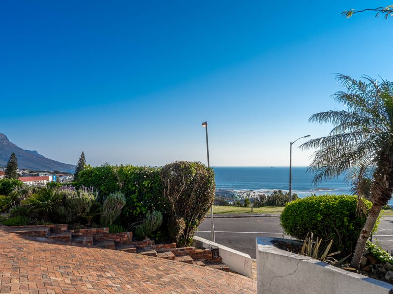 A scenic elevated view overlooking the coastline and ocean, featuring a brick-paved driveway and landscaped garden in the foreground.