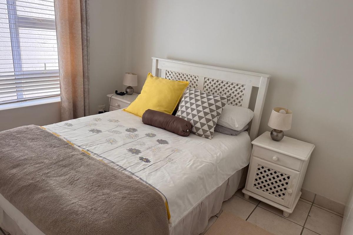 A functional bedroom featuring tiled flooring and a window with fitted blinds, providing a neutral base for interior design updates.