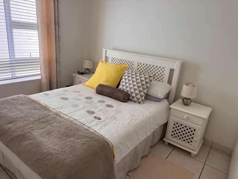 A functional bedroom featuring tiled flooring and a window with fitted blinds, providing a neutral base for interior design updates.