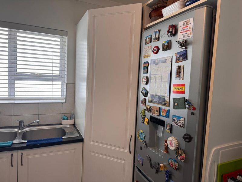 A functional kitchen area featuring a stainless steel double sink, tiled splashback, and built-in cabinetry with integrated storage.