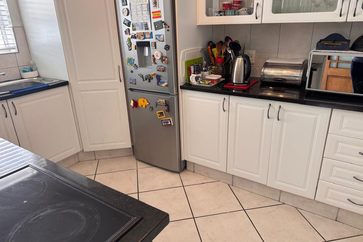 A functional kitchen featuring white cabinetry, dark granite countertops, ceramic tile flooring, and a built-in electric hob.