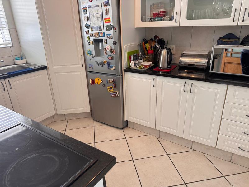A functional kitchen featuring white cabinetry, dark granite countertops, ceramic tile flooring, and a built-in electric hob.