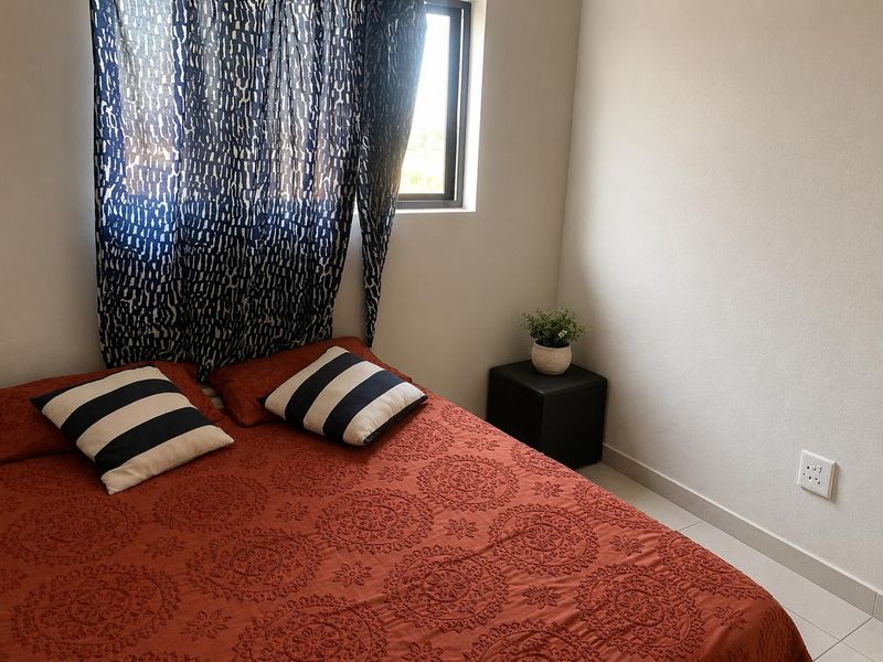 A compact bedroom featuring tiled flooring, neutral wall finishes, and an aluminium-framed window.