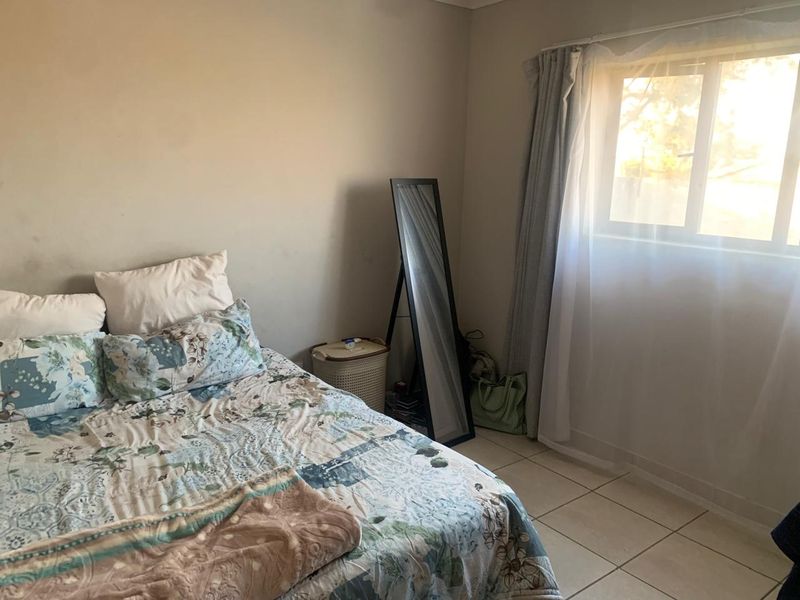 A standard bedroom featuring tiled flooring and a window with natural light, providing a functional space ready for cosmetic updates.