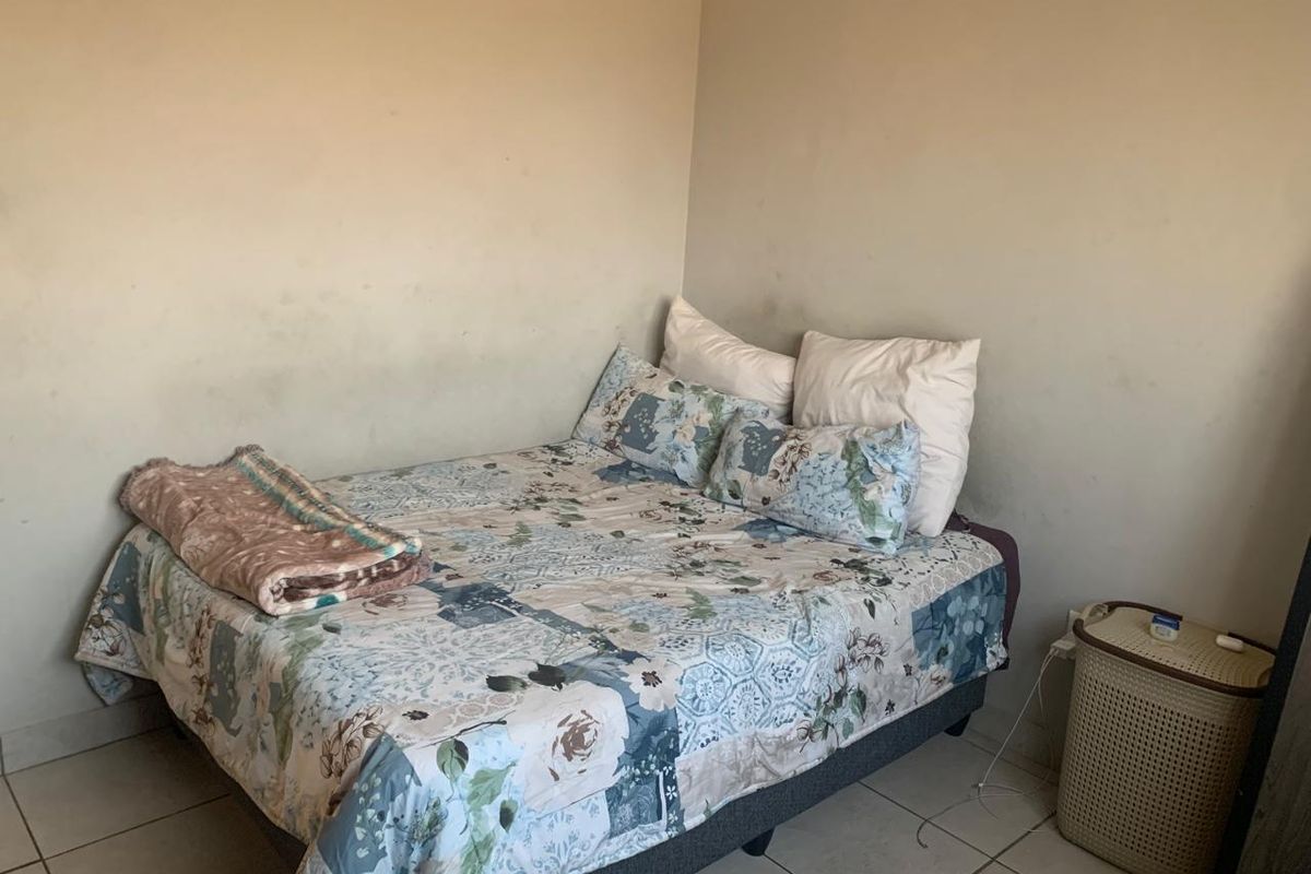 A bedroom featuring tiled flooring and plain walls that require repainting to refresh the space.