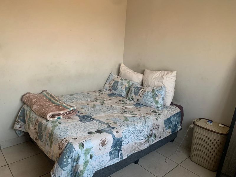 A bedroom featuring tiled flooring and plain walls that require repainting to refresh the space.