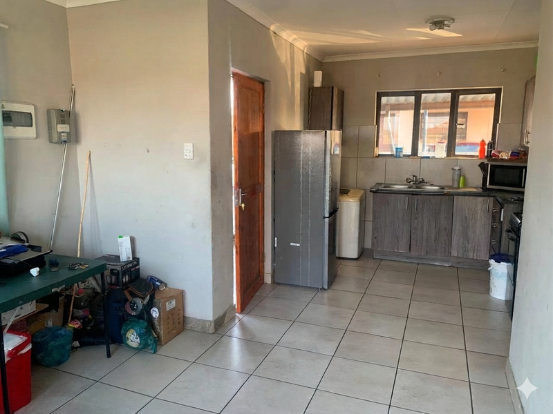 A functional kitchen area featuring tiled flooring, built-in cabinetry, and a double basin sink, requiring cosmetic updates to improve its overall condition.