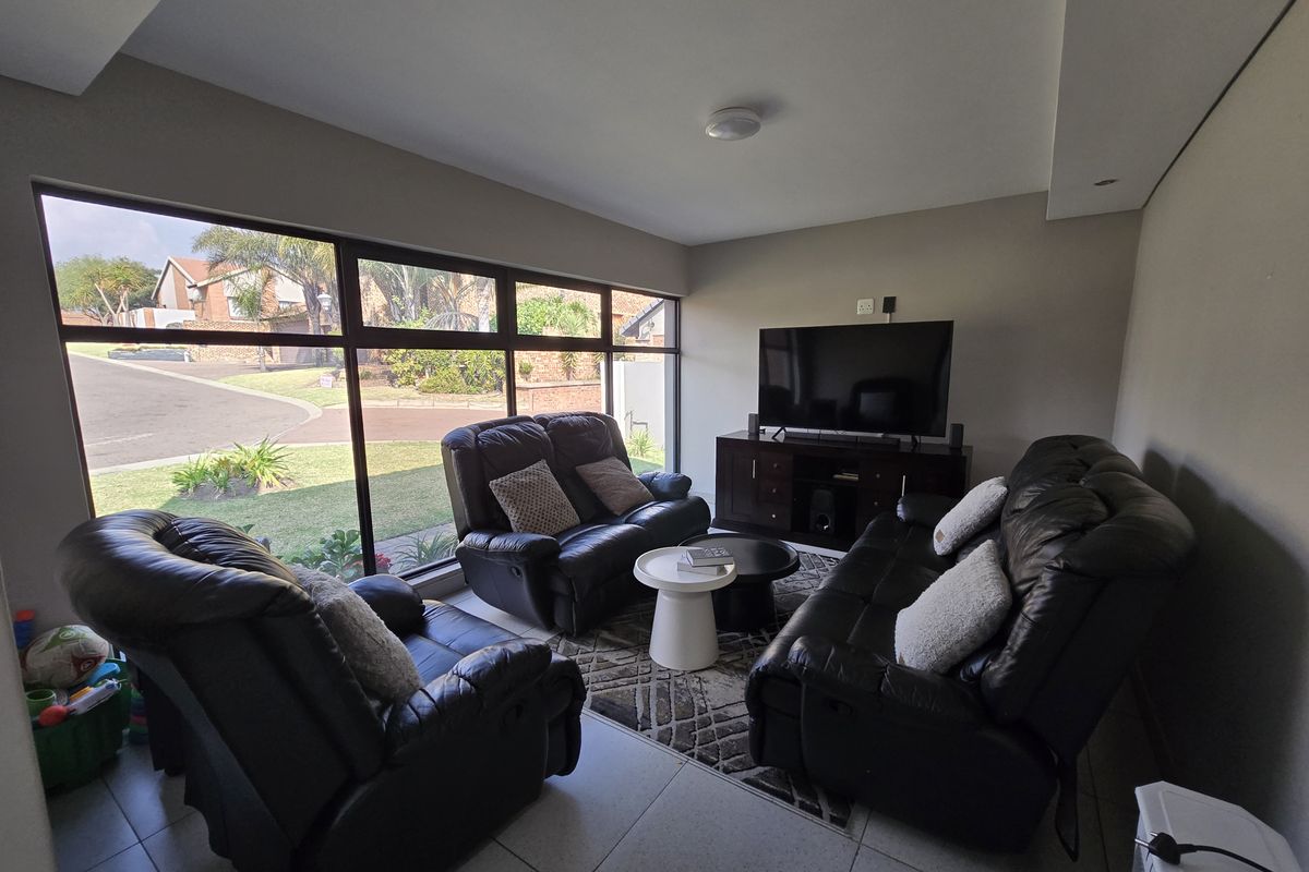 A bright living room featuring large floor-to-ceiling windows that provide ample natural light and views of the surrounding neighborhood.