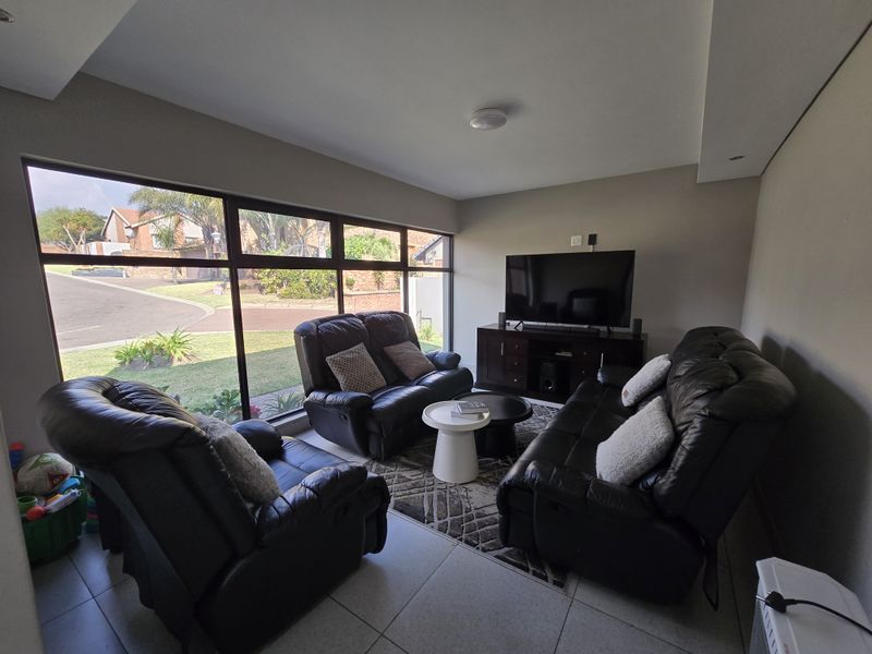 A bright living room featuring large floor-to-ceiling windows that provide ample natural light and views of the surrounding neighborhood.