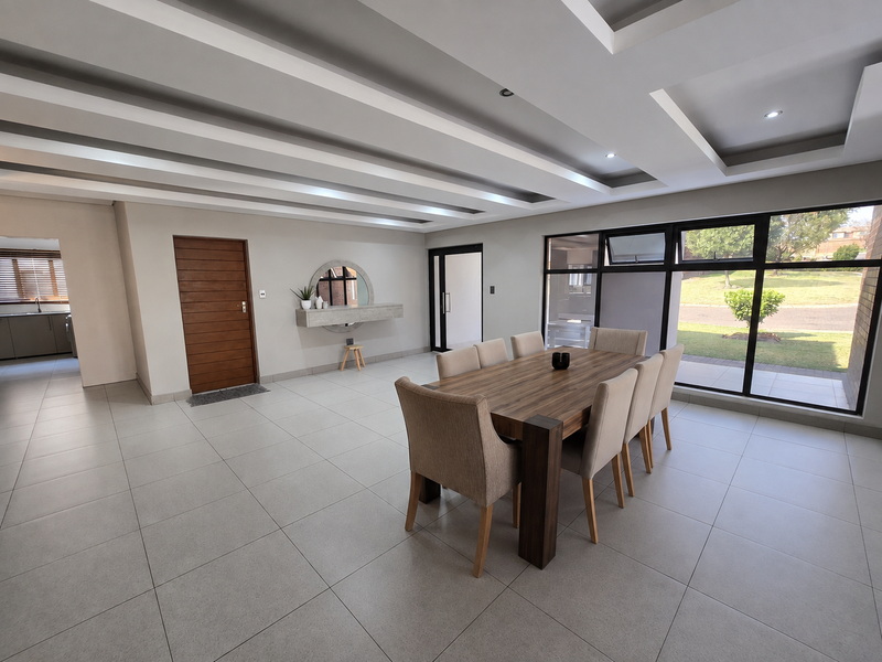 Spacious dining area featuring modern coffered ceiling design, large format floor tiles, and expansive windows providing natural light and garden views.