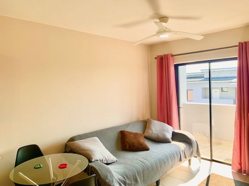 A living room featuring tiled flooring, a ceiling fan, and a sliding glass door providing access to an outdoor balcony area.