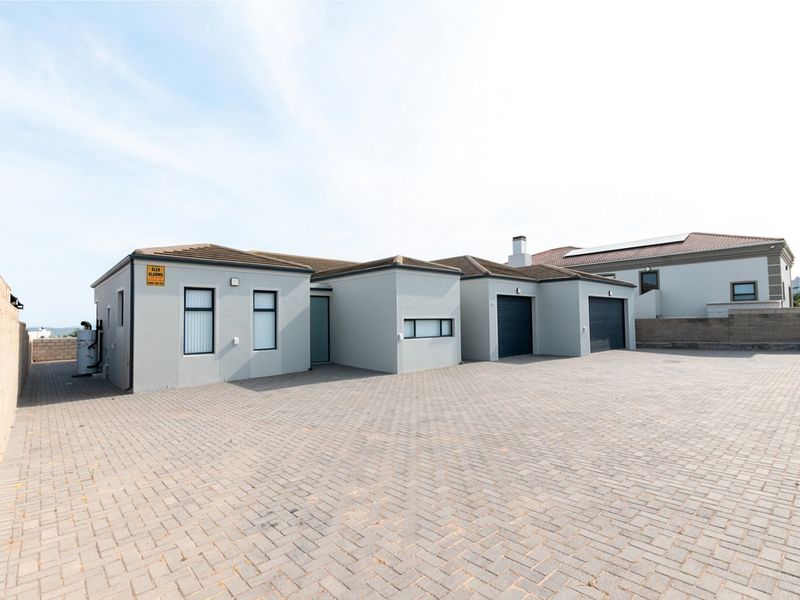 Front exterior view of a modern house featuring a paved driveway, double garage, and neutral rendered facade.