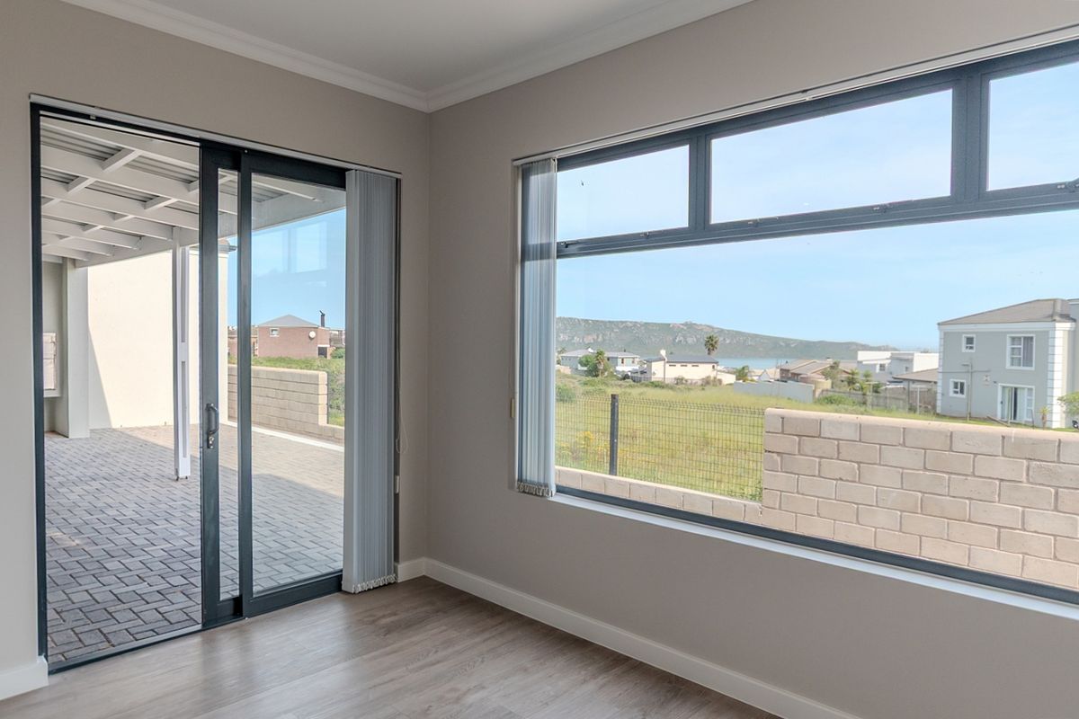 Bright and spacious living area featuring modern laminate flooring, large windows with scenic views, and direct access to an outdoor patio space.