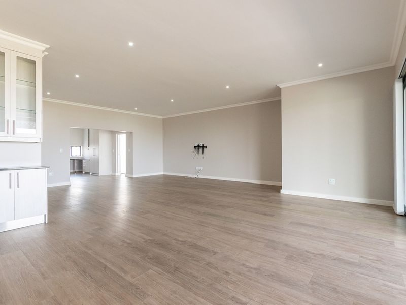Spacious open-plan living area featuring modern laminate flooring, recessed downlights, and large sliding glass doors leading to the exterior.