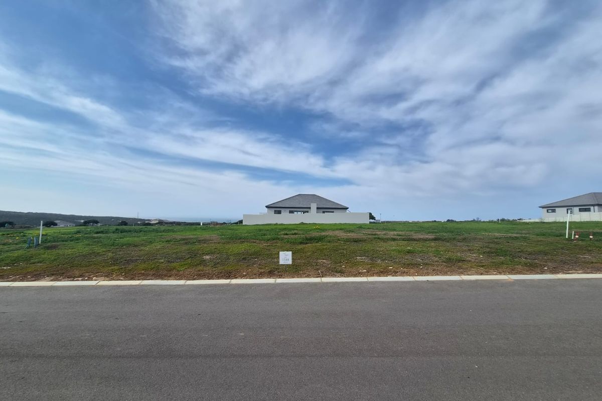 A vacant residential plot of land situated along a paved road, offering a clear view of the surrounding neighborhood and landscape.