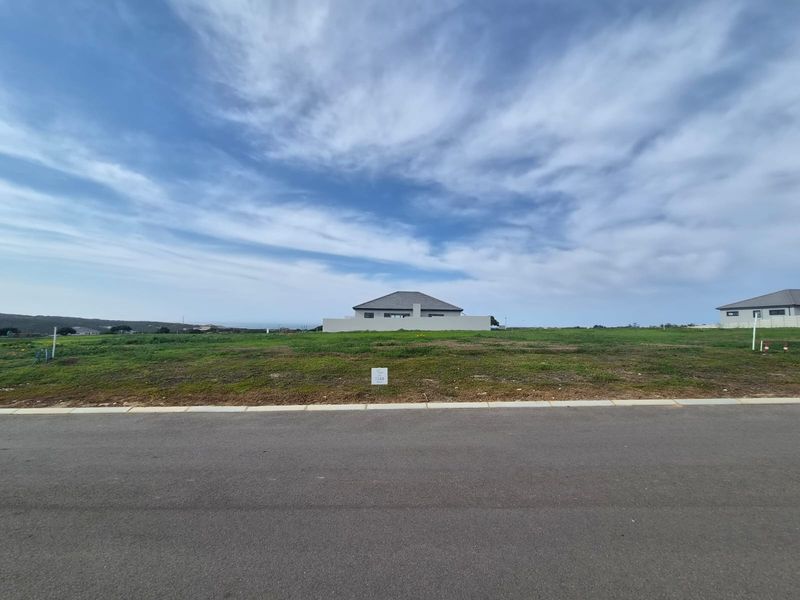 A vacant residential plot of land situated along a paved road, offering a clear view of the surrounding neighborhood and landscape.