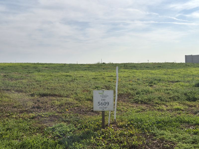 A vacant residential plot of land measuring 617 square meters, featuring a clear boundary marker and open grassy terrain.