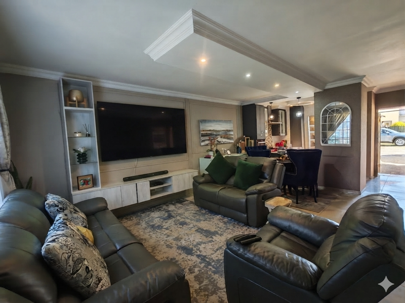 Spacious open-plan living area featuring a recessed ceiling with downlights, built-in media cabinetry, and an elegant arch-top wall niche.
