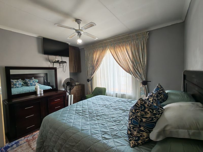 A comfortable bedroom featuring a ceiling fan and built-in cabinetry, offering a functional space with natural light through window curtains.