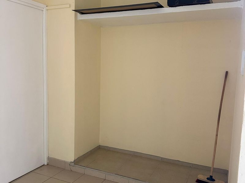 A functional utility space featuring tiled flooring and a built-in storage shelf, suitable for laundry or general storage purposes.