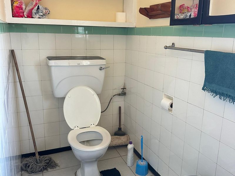 A functional bathroom featuring a standard toilet, wall-mounted storage shelving, a medicine cabinet, and tiled wall and floor finishes.