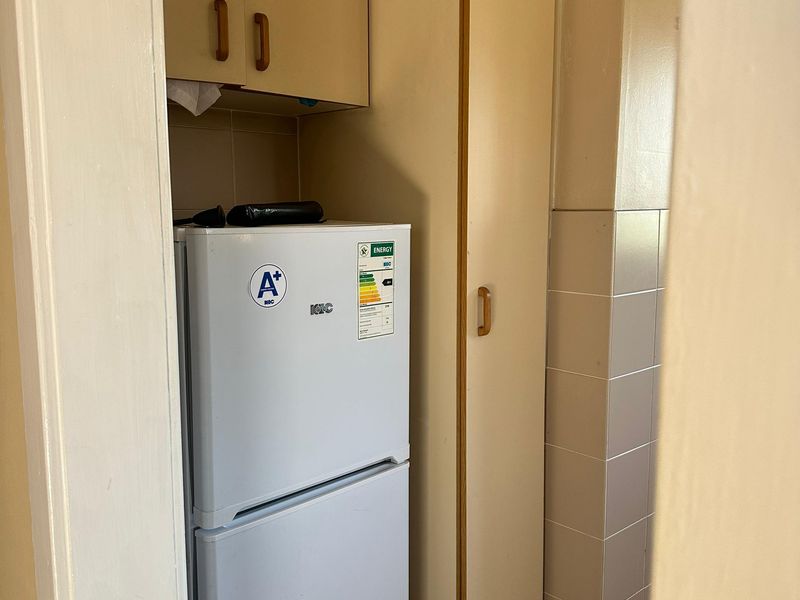 A compact scullery or utility area featuring built-in cabinetry and tiled splashback finishes.