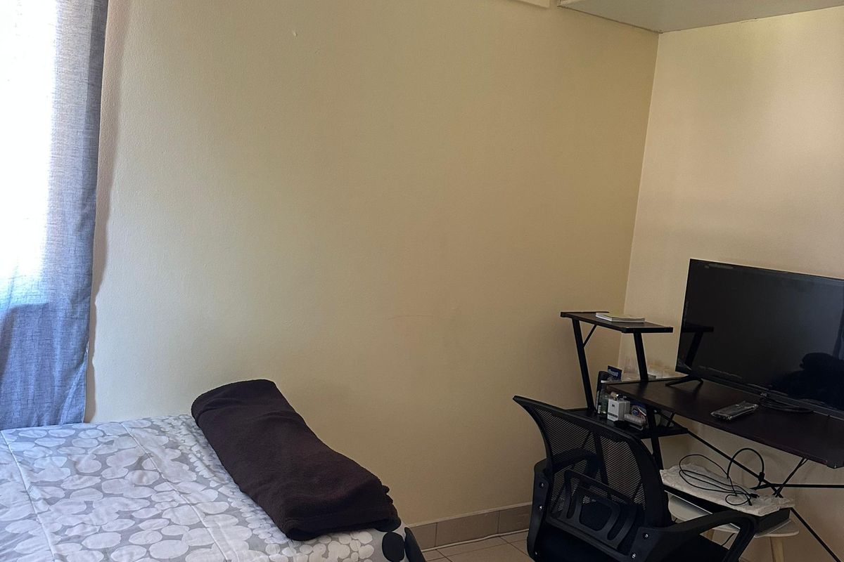 A functional bedroom featuring tiled flooring and built-in overhead storage cabinetry, providing a practical layout for a compact living space.