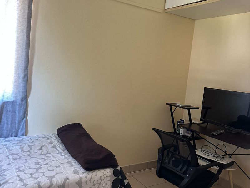 A functional bedroom featuring tiled flooring and built-in overhead storage cabinetry, providing a practical layout for a compact living space.