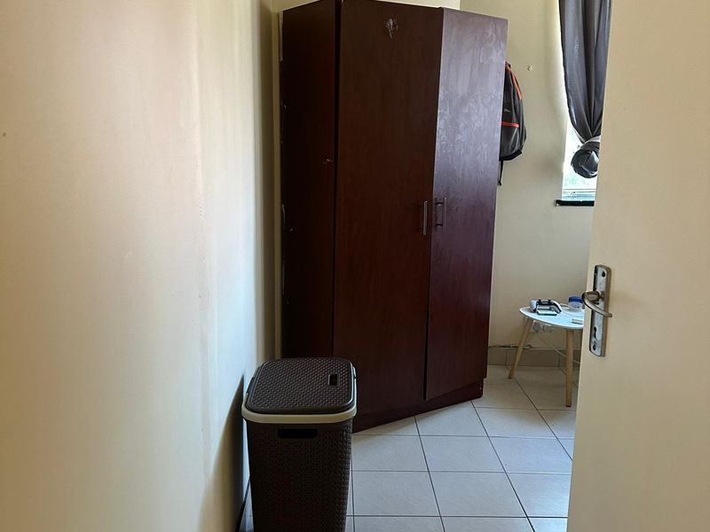 A compact bedroom featuring tiled flooring and a window, providing a functional space ready for personalization.