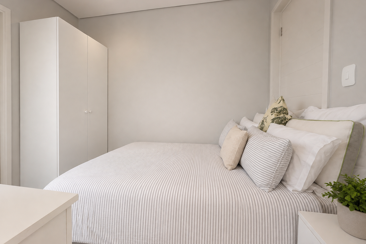 A well-maintained bedroom featuring a built-in wardrobe, recessed downlighting, and a subtle panelled feature wall, offering a clean and modern aesthetic.