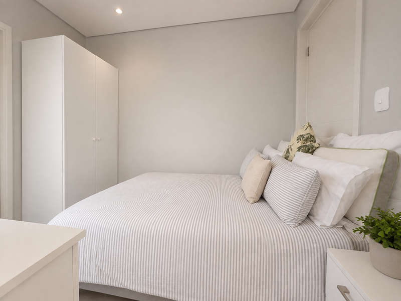 A well-maintained bedroom featuring a built-in wardrobe, recessed downlighting, and a subtle panelled feature wall, offering a clean and modern aesthetic.