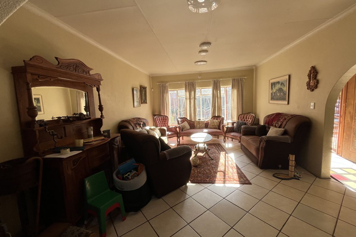 A spacious living room featuring tiled flooring, an arched entryway, and natural light streaming through large windows.