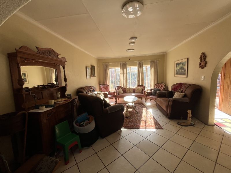 A spacious living room featuring tiled flooring, an arched entryway, and natural light streaming through large windows.