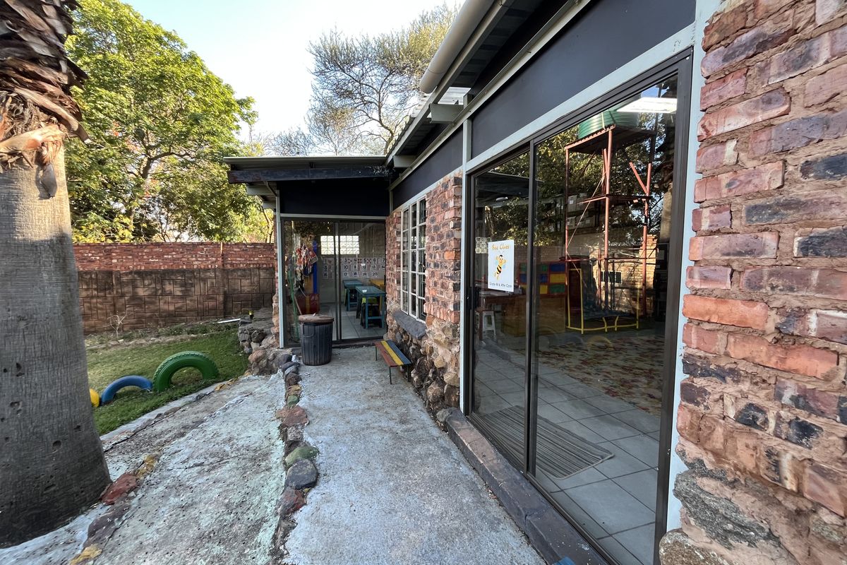 Rear exterior view of the property featuring exposed brick walls, stone masonry detailing, and sliding glass doors leading to a concrete walkway.